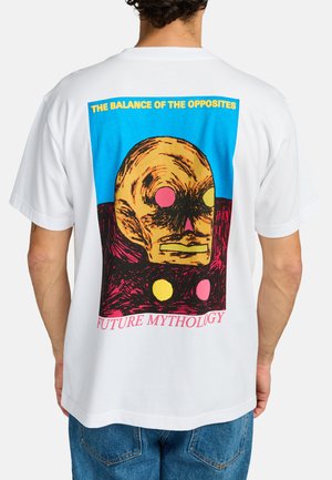 White cotton t-shirt featuring a colorful graphic of a skull-like face, with blue, pink, yellow, and black accents, and text at the bottom.