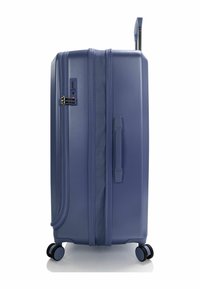 Hartschalenreisekoffer in Dunkelblau, ausgestattet mit einem seitlichen Griff, Reißverschluss und Zahlenschloss. Vier schwarze Rollen für Mobilität und ein elegantes Design.
