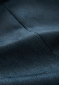 Tissu bleu marine avec une texture douce et lisse. Légère brillance avec de légères variations de couleur, comportant une couture au centre.