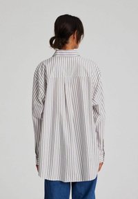 Striped long-sleeve shirt in light colors, featuring a collar, buttoned cuffs, and a relaxed fit with a back yoke detail.