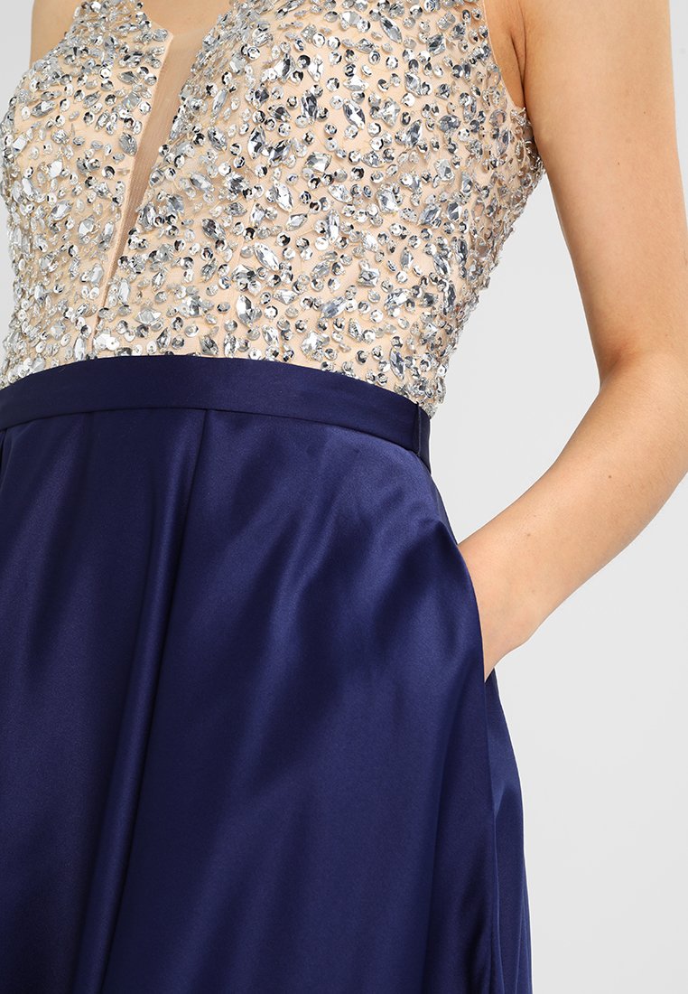 Granatowa sukienka z dopasowanym topem, ozdobionym przezroczystym dekoltem z aplikacjami, wysadzanym srebrnymi koralikami, oraz satynowym, rozkloszowanym dołem.