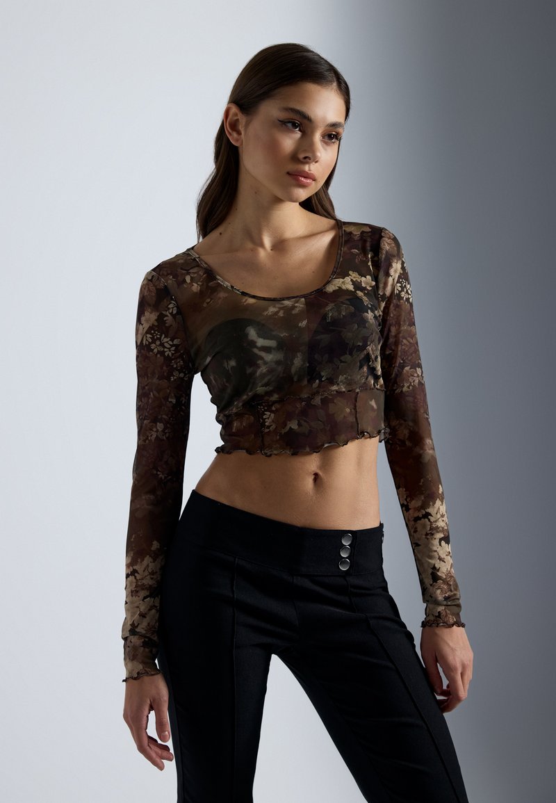 Bruin bloemenprint doorschijnende blouse met lange mouwen en een cropped zoom, ronde halslijn en scalloped randen, in combinatie met hoge taille zwarte broek met knoopaccenten.