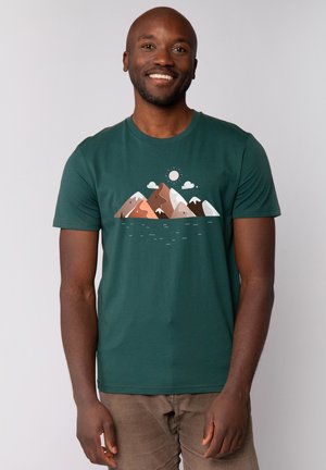 Groene katoenen T-shirt met een grafisch ontwerp van bergen in bruintinten en wit, met wolken en een zon. Korte mouwen, ronde hals.