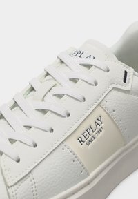 Λευκό δερμάτινο αθλητικό παπούτσι με λευκά κορδόνια και την επιγραφή "REPLAY SINCE 1981" στο πλευρικό πάνελ.