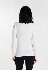 Pulover alb din tricot cu mâneci lungi, având un model subtil de puncte texturate, cu manșete și tiv cu nervuri. Vedere din spate, prezentată pe un fundal deschis.
