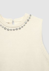 Gestrickter cremefarbener Pullover mit einem gerippten Kragen, der eine Reihe dekorativer silberfarbener Steine entlang des Halsausschnitts und eine Schlüsselöffnung hinten aufweist.