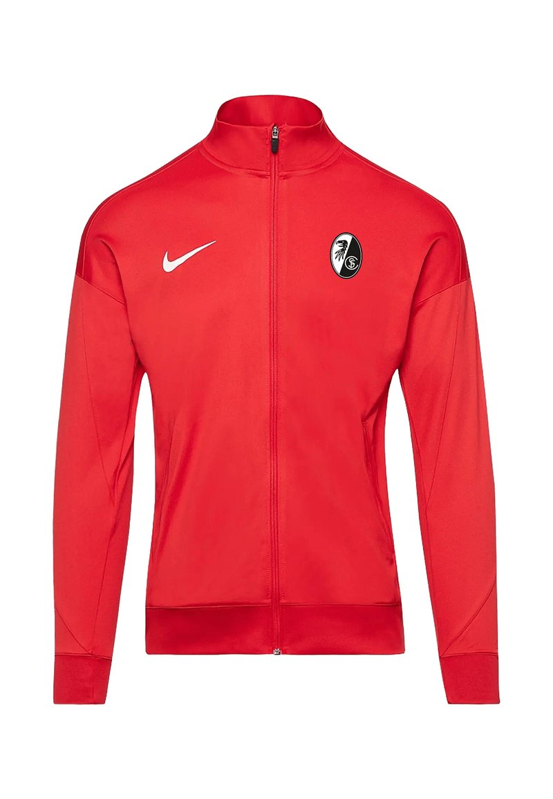 Rode sportjack met een volledige rits, gemaakt van gladde stof, met een wit Nike-logo en een zwart-wit teamembleem op de borst.