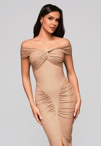 Beige off-the-shoulder mekko, jossa on koottu kangas, tiukka siluetti ja pystysuora rypytys, jossa on reisi korkealla oleva halkio ja sileä pinta.