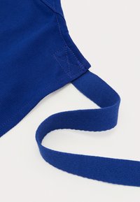 Blue fabric face mask featuring a textured surface, adjustable woven straps, and reinforced stitching detail at the edges.