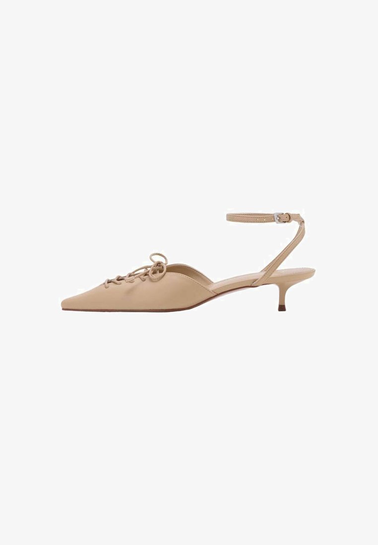 Escarpin slingback en cuir beige avec un bout pointu et un délicat détail de lacets. Il est doté d'une fine bride de cheville et d'un petit talon.