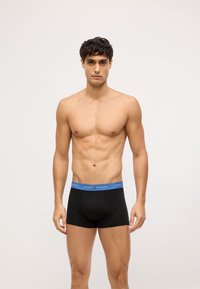 Boxer ajustados negros con una cinturilla azul que presenta el logotipo "TOMMY HILFIGER". La tela se ve suave y ajustada, con un corte clásico.