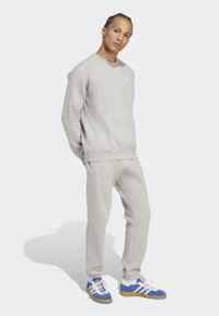 Ljusgrå sweatshirt och sweatpants i mjukt tyg. Sneakers med blå accenter och vita ränder, med en strukturerad sula.