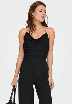 Top de satén negro con escote drapeado, tirantes adornados con plata, combinado con pantalones negros de tiro alto. Textura suave, diseño minimalista.