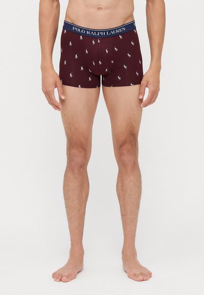 Burgundi színű boxernadrág sötétkék derékkal, ismétlődő fehér póló játékos logó mintázattal. Puha, rugalmas anyag.