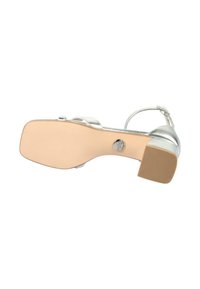 Silver heeled sandal featuring a smooth metallic upper, open toe, strap design, and textured rubber sole for traction. Adjustable ankle strap included.