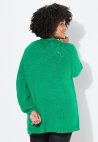 Maglione verde lavorato a maglia con una vestibilità morbida, spalle basse e un motivo testurizzato. Presenta un collo rotondo e un orlo a coste.