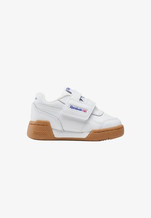 Witte Reebok-sneaker met lichtbruine rubberen zool, twee klittenbandsluitingen en logo op de zijkant en tong, gezien van de buitenkant.