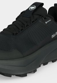 Μαύρο ορειβατικό παπούτσι Gore-Tex με παχιά σόλα, υφασμάτινο άνω μέρος με υφή, μαύρα κορδόνια και λογότυπο στη γλώσσα και στο πλάι.