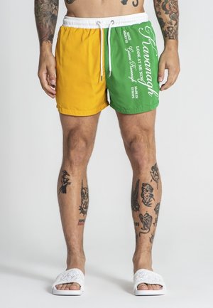 Shorts de bain en color block avec des panneaux jaunes et verts, taille élastique avec cordon de serrage, et texte imprimé en blanc.