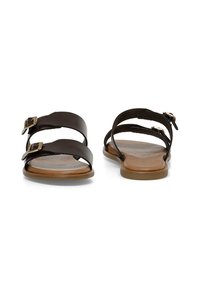 Brown leather sandals with two adjustable straps, gold buckle accents, and a flat, tan sole. Smooth texture and open-back design.