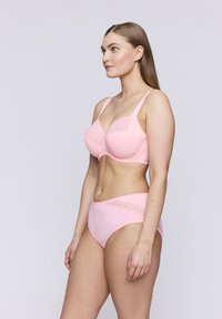 Rosa bh och matchande högmidjade trosor med spetsdetaljer, slät tyg och en strukturerad design, som framhäver en figurnära siluett.