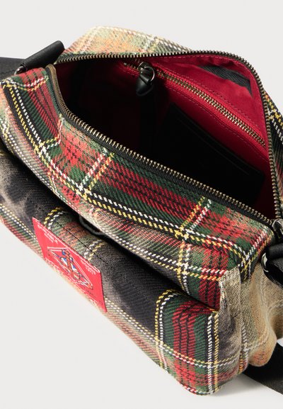 Karirana torba z mešanico zelenih, rdečih in rumenih vzorcev. Notranjost ima rdečo podlogo in žep na zadrgo. Trda tkanina in kovinska zadrga.