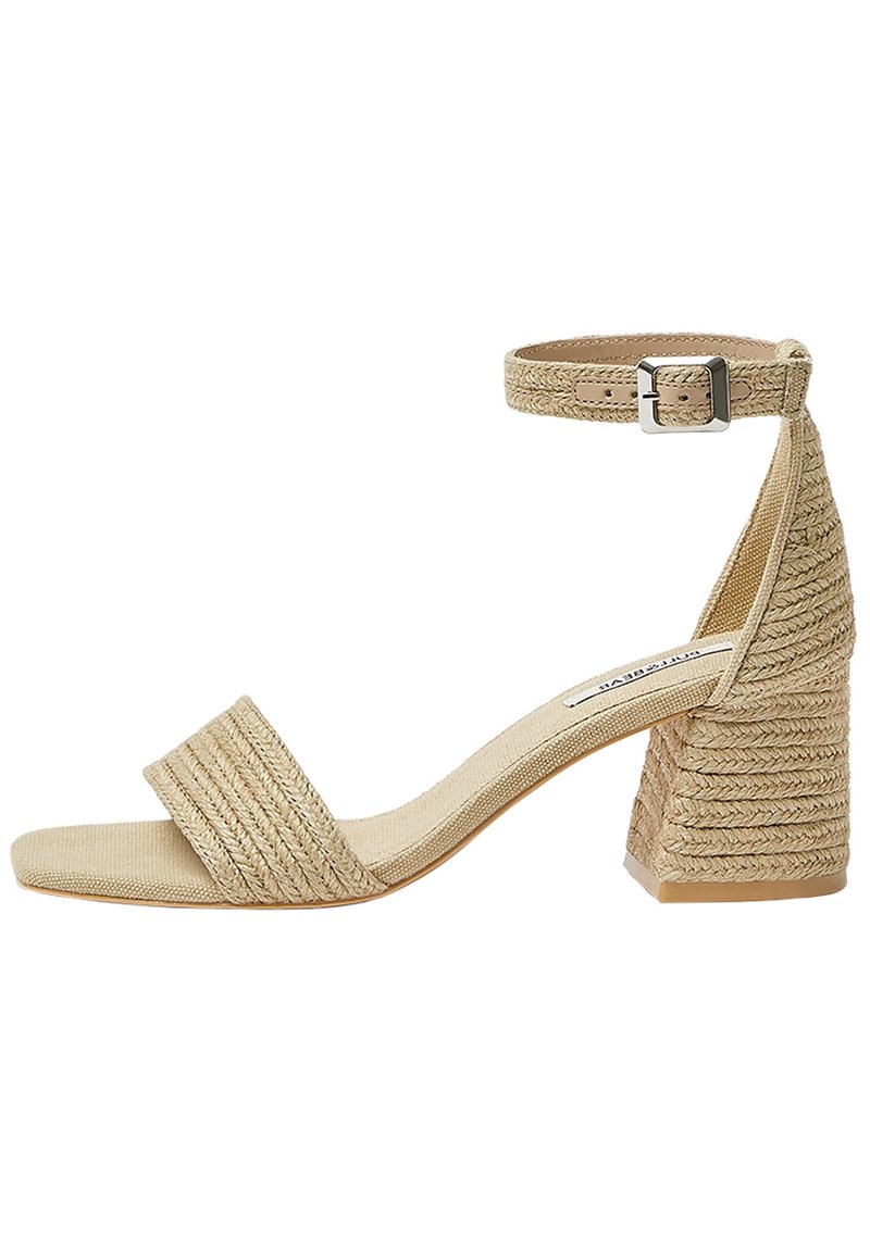 Sandale à talon beige avec une tige en tissu texturé, une bride à la cheville et un talon bloc orné de détails tissés. Dessus ouvert.