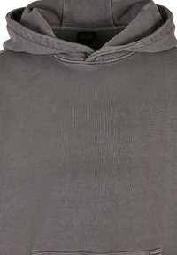 Felpa grigia con una texture morbida, dotata di cappuccio con cordoncino e tasca a marsupio. Design semplice con polsini e orlo a coste.