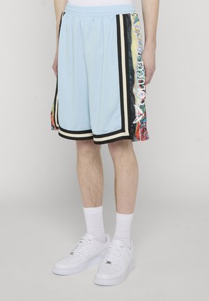 Lyseblå atletiske shorts med sort og hvid kant samt farverige mønstrede sidepaneler, båret med hvide sokker og hvide sneakers.