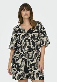 Ensemble bicolore noir et crème comprenant un haut à col en V avec des manches larges et un short assorti avec une taille élastique.
