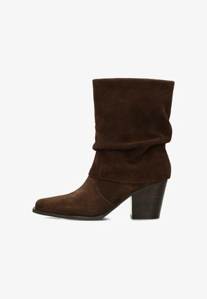 Brauner Wildleder-Mittelschaftstiefel mit rund zulaufender Kappe, gestapeltem Blockabsatz und schwarzer Sohle.