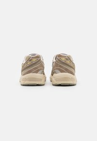 Brune semskede og mesh sneakers med beige detaljer, som har en polstret såle og buede designelementer på siderne.
