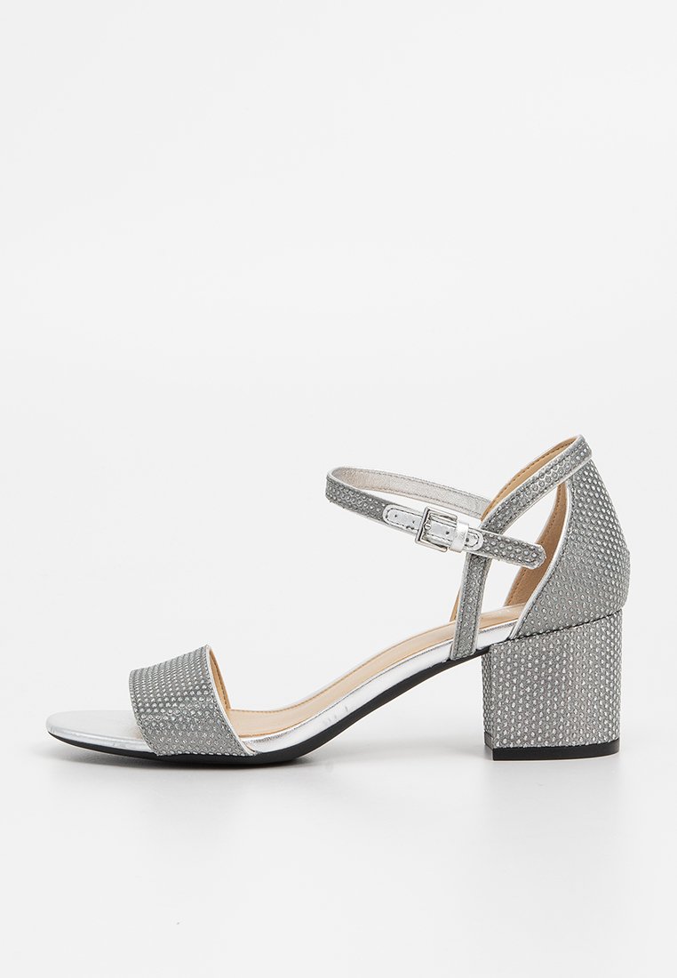 Sandale à talon haut grise avec une bride de cheville, dessus texturé, orteils ouverts et talon carré. Comprend des accents argentés et une doublure intérieure lisse.