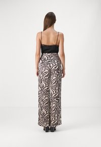 Black lace-trimmed camisole top with spaghetti straps paired with wide-leg pants featuring a beige and dark brown zebra print pattern.