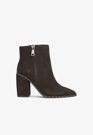 Botín de ante gris oscuro con puntera afilada, tacón cuadrado, cremallera lateral y detalles de tachuelas metálicas a lo largo de la suela. Textura suave.