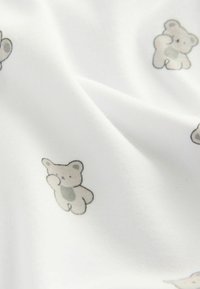 Weißer Stoff mit einem sich wiederholenden Muster aus kleinen, hellgrauen Teddybären mit dezenten Details. Die Textur wirkt weich und glatt.