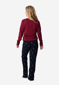 Top burdeos de manga larga con cuello redondo, combinado con pantalones de pijama azul marino que tienen un pequeño estampado. Tela de algodón suave.
