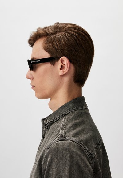 Black rectangular sunglasses with a glossy finish. The frame features a logo on the side. Worn with a dark gray denim shirt.