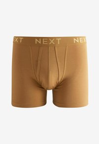 Tronc en coton marron avec une taille moyenne, arborant le mot "NEXT" en lettres dorées, un design ajusté et une texture lisse.