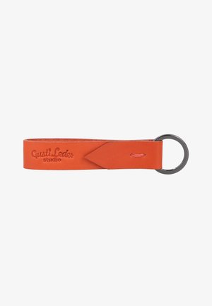 Orange leather keychain strap with embossed "Gusti Leder studio" text and a metal keyring attached at one end.