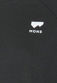 Svart skjorta med en slät textur och en liten vit logotyp med geometriska former samt texten "MONS" på övre vänstra sidan.