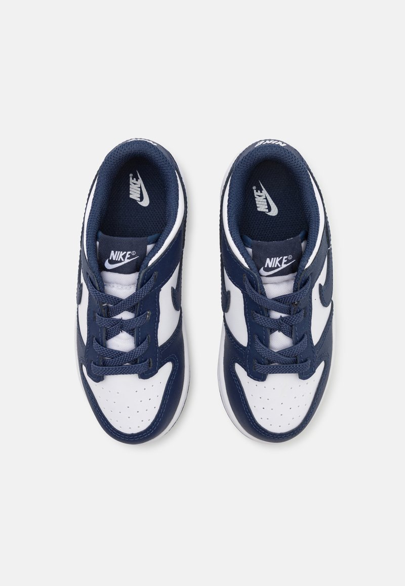 Des baskets Nike bleu marine et blanches dotées d'un dessus en cuir et textile, d'un bout arrondi, de détails perforés et d'un système de laçage classique.
