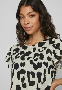Leopardmönstrad t-shirt i ljusgrått med svarta mönster. Har korta ärmar och en avslappnad passform, tillverkad av mjukt och lätt tyg.