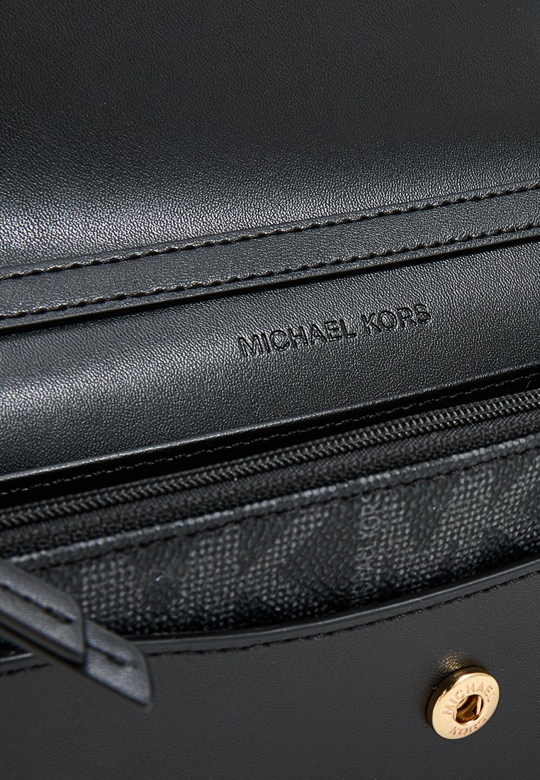 Zwarte leren tas met een ritsluiting, een textuur interieur en het reliëflogo "MICHAEL KORS". Inclusief details in goudkleurige hardware.