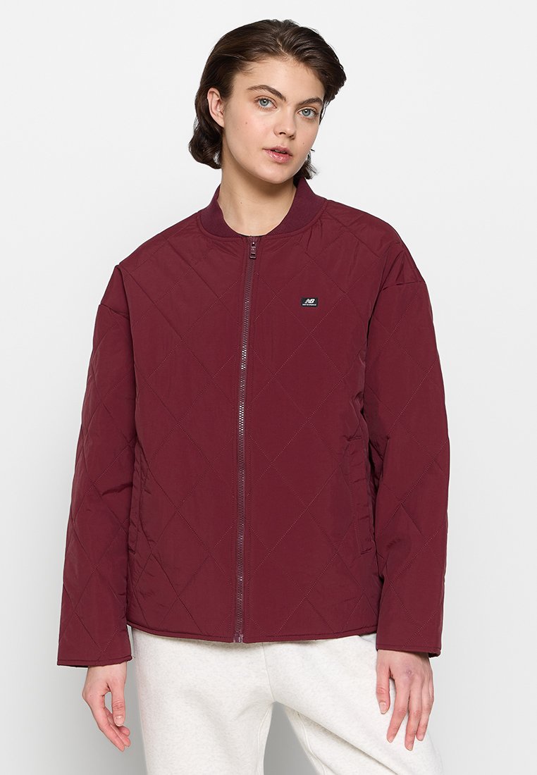 Chaqueta acolchada burdeos con cuello redondo, cremallera frontal y pequeño detalle de logo. Tejido suave con un corte holgado y mangas largas.