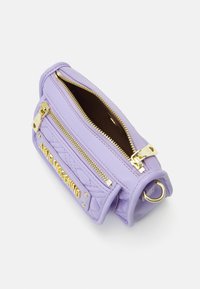 Fialová kožená kabelka s prošívaným designem, obsahující zlaté kování, dvojité zipy a boční kroužek na připevnění popruhů.