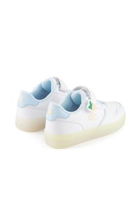 Białe sneakersy z jasnoniebieskimi akcentami, skórzany materiał, płaski 디자인, okrągły czubek i dekoracyjny urok w postaci ananasa na pasku.