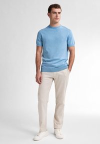 Pulover tricotat bleu deschis cu mânecă scurtă; guler rotund; asortat cu pantaloni din in bej și adidași albi; textură netedă; design ajustat.