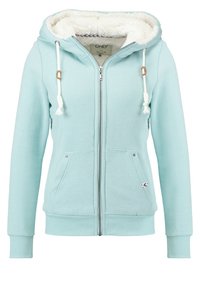 Felpa con zip di colore blu chiaro, foderata in morbido pile bianco, con doppi lacci e tasche frontali. Polsini e orlo a coste; esterno in cotone liscio.