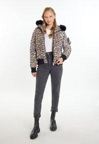 Giacca bomber in stampa leopardata con cappuccio in finta pelliccia nera, polsini e orlo a coste, abbinata a pantaloni grigi a vita alta e stivaletti neri.